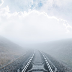 zbliżenie kolejowe idzie do horyzontu we mgle pod zachmurzonym niebie - 180675458