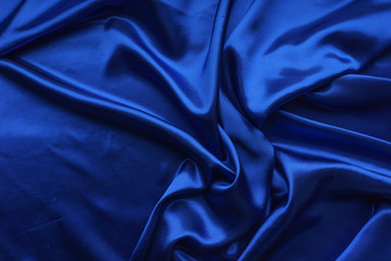 Blue satin, silky fabric, wave, draperies. Beautiful textile backdrop. Close-up. Top view 