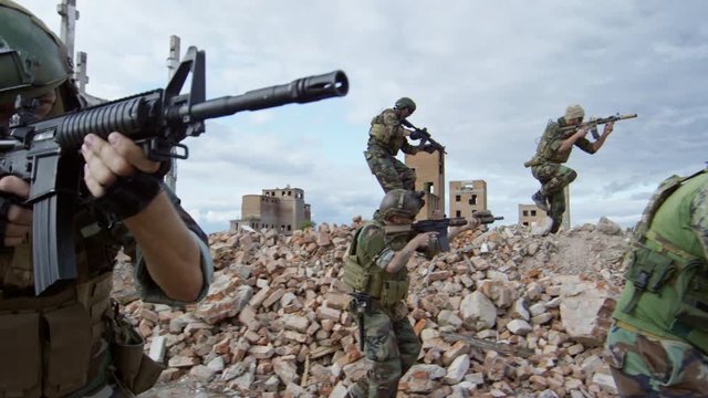 SLOWMO of team of soldiers aiming shotguns while walking on urban ruins