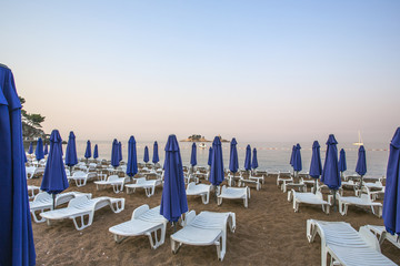a deserted beach with sun loungers and umbrellas in the early morning.