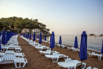 a deserted beach with sun loungers and umbrellas in the early morning.