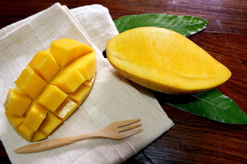 Sweet mango with wooden fork in white napkin on wood table