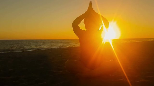 Woman's silhouette doing yoga against a beautiful sunset.

