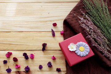 Red gift box with beautiful bow ,grass flower on white fabric on wood board background,top view for copy space
