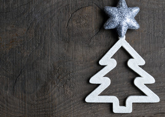 Christmas decoration.Decorative white fir tree with silver star on old wooden
background.Winter holidays,Merry Christmas concept.Copy space.Selective focus.