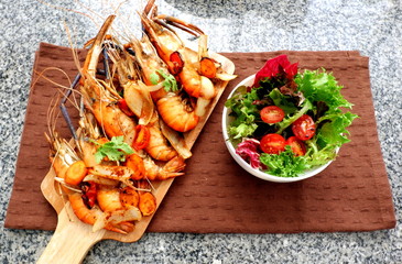 Grilled shrimp on wood board with vegetable and salad with brown napkin