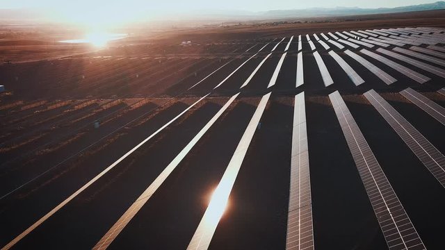 Aerial desert view large industrial Solar Energy Farm producing concentrated solar power. Around the mountain and the sun sets at sunset