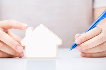 Woman holding the small home with white blank over the document .  Concept for real estate business.