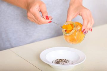 Woman holds spoon with turmeric