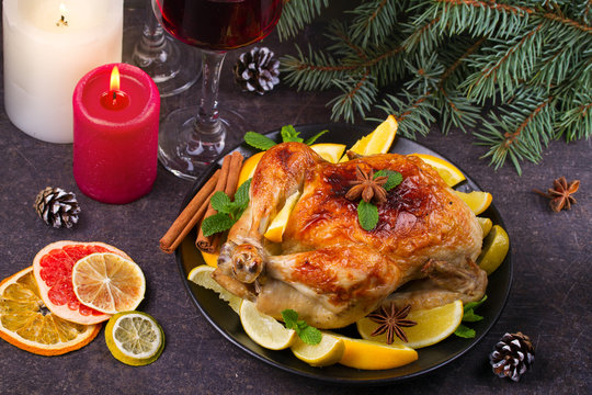 Chicken or turkey with lemons, oranges, limes and spices on Christmas and New Year background. Two glasses of wine, horizontal