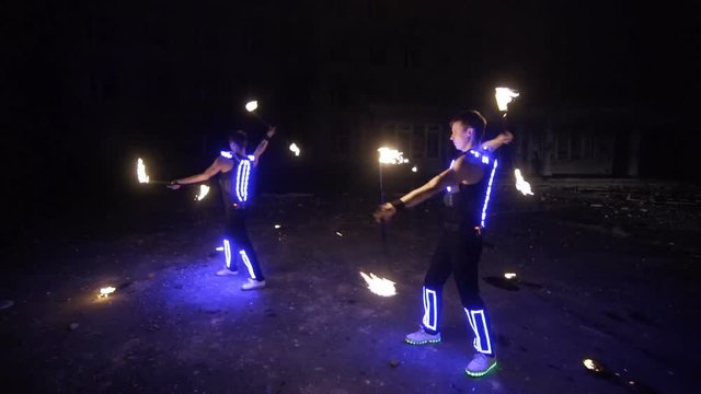 fire show, dancing with flame, a man in a suit LED dances with fire, draws a fiery figure in the dark