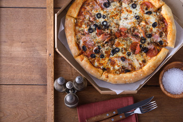 Rustic pizza with pepperoni sausage, mozzarella, olives and basil