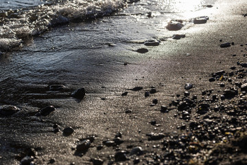 A close view of water on a lake shore, with details of sands and little stones