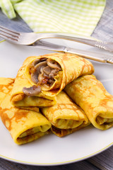 Wrapped thin pancakes  filled with mushrooms on white plate, vertical