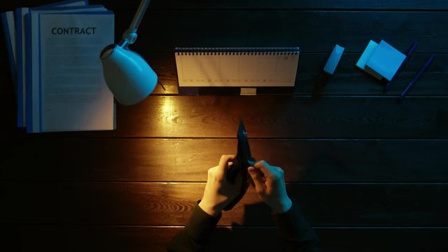 A man is sitting at an office desk and using a phone.