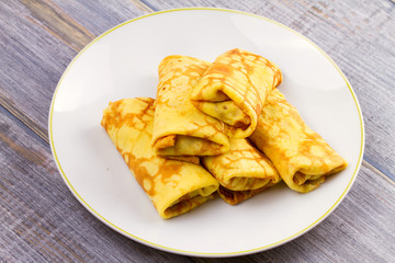 Wrapped thin pancakes  filled with mushrooms on white plate, horizontal