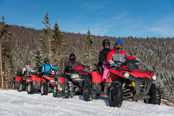 Group of people driving four-wheelers ATV bikes on snow in winter