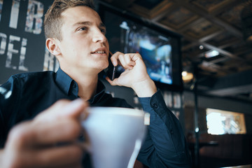 man talking on the phone with a mug of coffee in his hand