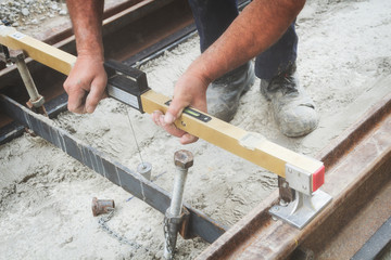 Construction worker leveling concrete pavement outdoors.