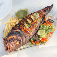 fried fish with lemon French fries and vegetables on white plate