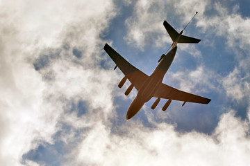 he plane on the background of blue sky with clouds in the rays of the sun.