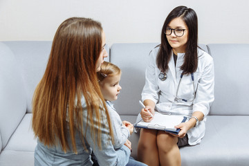 Little girl and her young mother are consulting with pediatrician in his office
