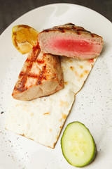 Medium rare beef steak on plate with lemon and cucumber