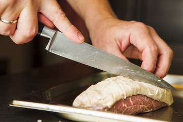 Butcher cuts fresh red meat going to prepare beefstrak