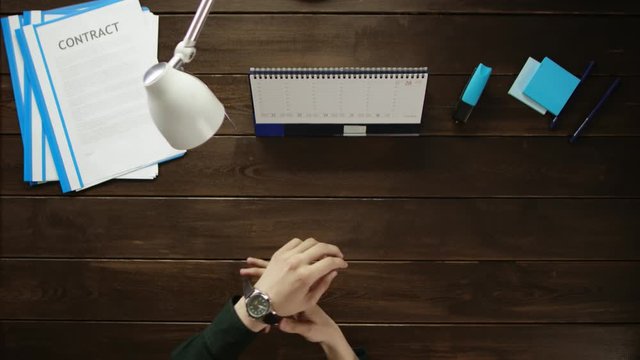 A man is sitting at an office desk and using a phone.