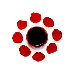 black drink in a red Cup in a frame of red rose petals, top view