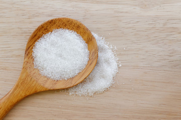 Fototapeta na wymiar White sugar in wooden spoon on wooden table