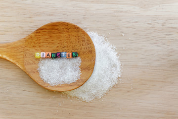 Diabetes concept. Alphabet with word DIABETES with sugar and wooden spoon on wooden background.