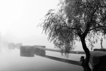 Poster de jardin Jetée Autumn landscape with river in black and white. Willow and wooden pier in morning mist. Ruined old bridge