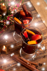 Christmas mulled wine with fruits and spices on wooden table.