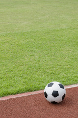 The football is on the green grass soccer field in the stadium.