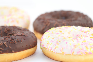 Four appetizing sweet white and chocolate donuts, close up view