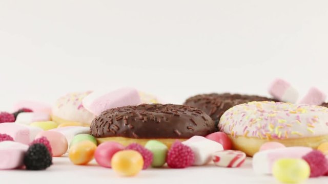 Donuts and candies and marshmallows on white table