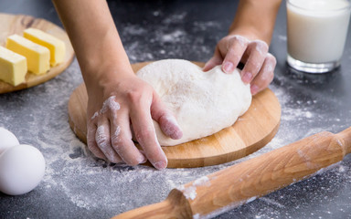 Making dough by female hands on wooden table background