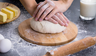 Making dough by female hands on wooden table background