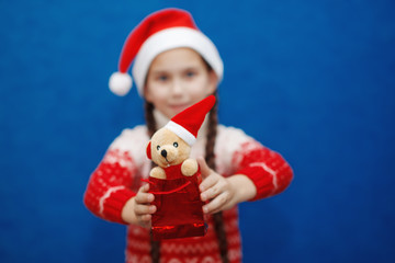 Cute little girl with toy on background of blue color. Christmas concept