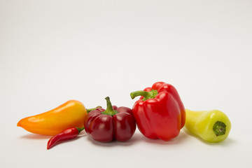 Several ripe sweet and hot peppers of red and orange on a white background