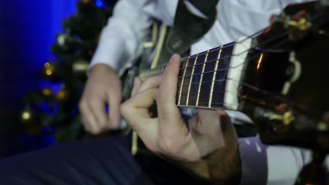 Close-up Guitarist Playing Electro Guitar on the background of Christmas tree