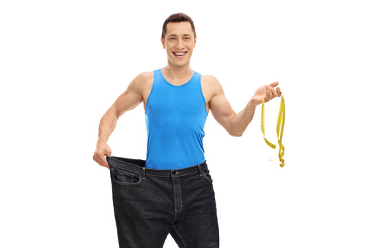 Man in a pair of oversized jeans holding a measuring tape