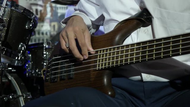 close up jazzman playing the bass guitar in the rays of light concert,