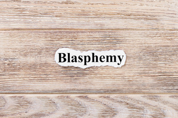 BLASPHEMY of the word on paper. concept. Words of BLASPHEMY on a wooden background