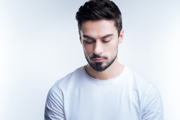 Obraz premium Looking down. Handsome young calm man looking down at his beautiful fashionable new shoes while standing against the blue background