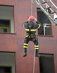 brave rescuer with red helmet descends from the platform during