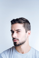 Obraz premium Doubting man. Smart experienced handsome man looking thoughtful while sitting against the blue background and having doubts about the deal with his business partner