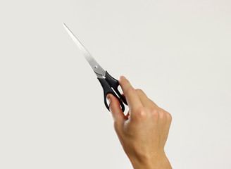 Male hands holding black scissors. Isolated on gray background. Closeup