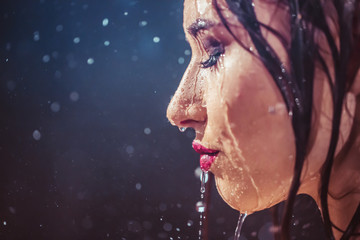 Close up portrait of sexy wet brunette girl wears black top under rain splashes